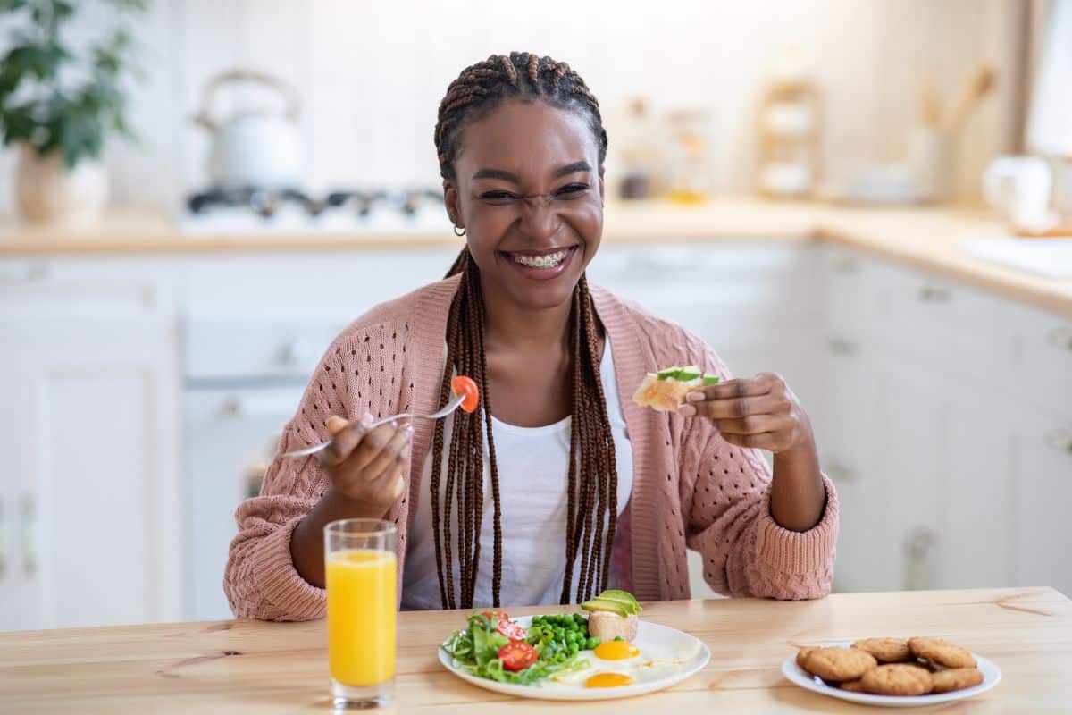 What to Eat During Your First Week with Braces Woman enjoying healthy meal with salad and juice in bright kitchen setting