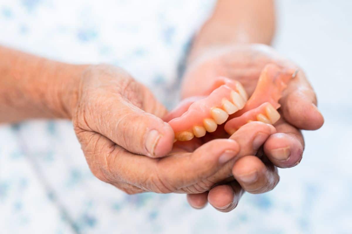 Dentures Elderly person holding a set of removable dentures in their hands.