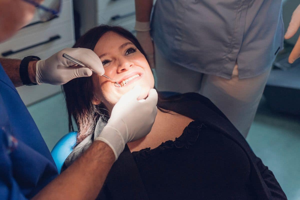 Woman smiling during a dental checkup with her dentist.