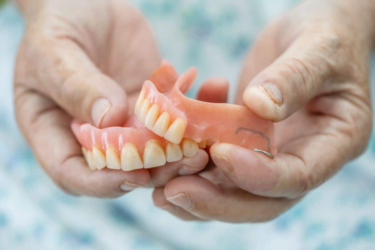Dentures Elderly hands holding upper and lower dentures for relining and repair in Rio Rancho.