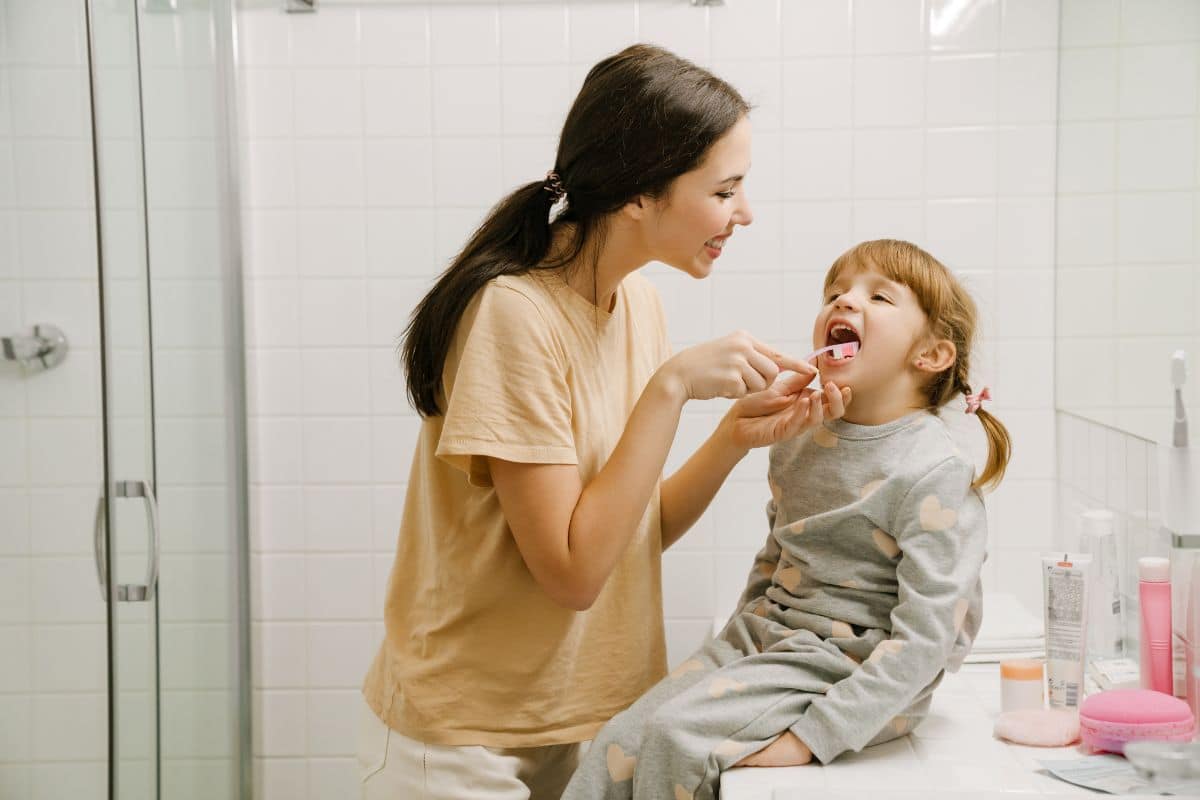 A parent helping a young child brush their teeth Child brushing teeth with a parent helping.