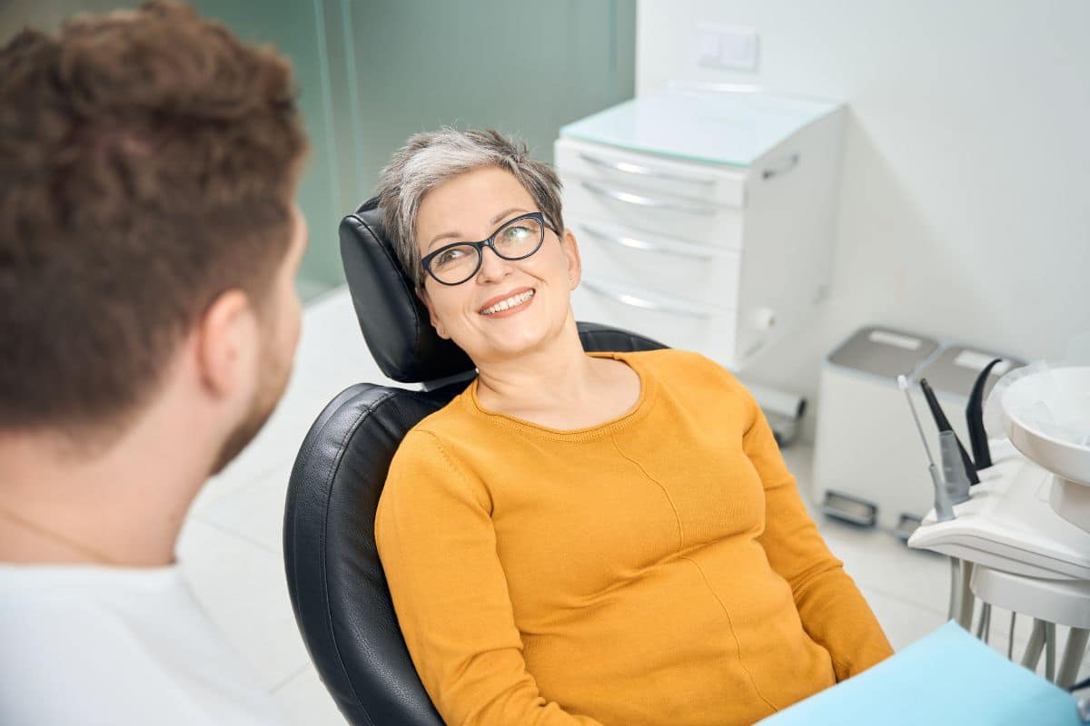 Smiling Patient An older woman smiling confidently while talking with her dentist during a dental implant consultation.