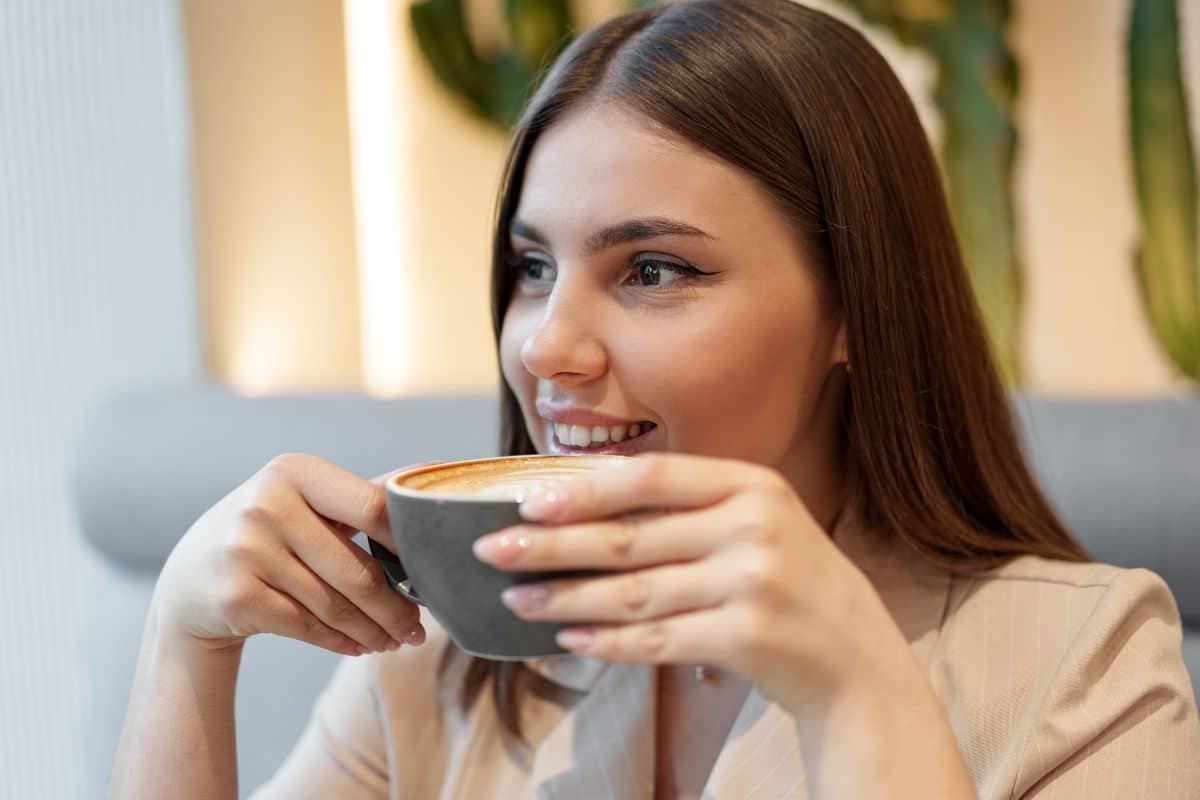 Person enjoying a cup of coffee while following Invisalign care habits.